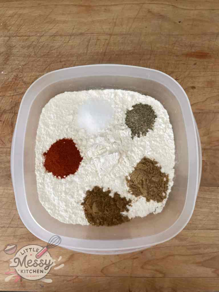 Flour, coriander, paprika, cumin, salt and pepper in a bowl.