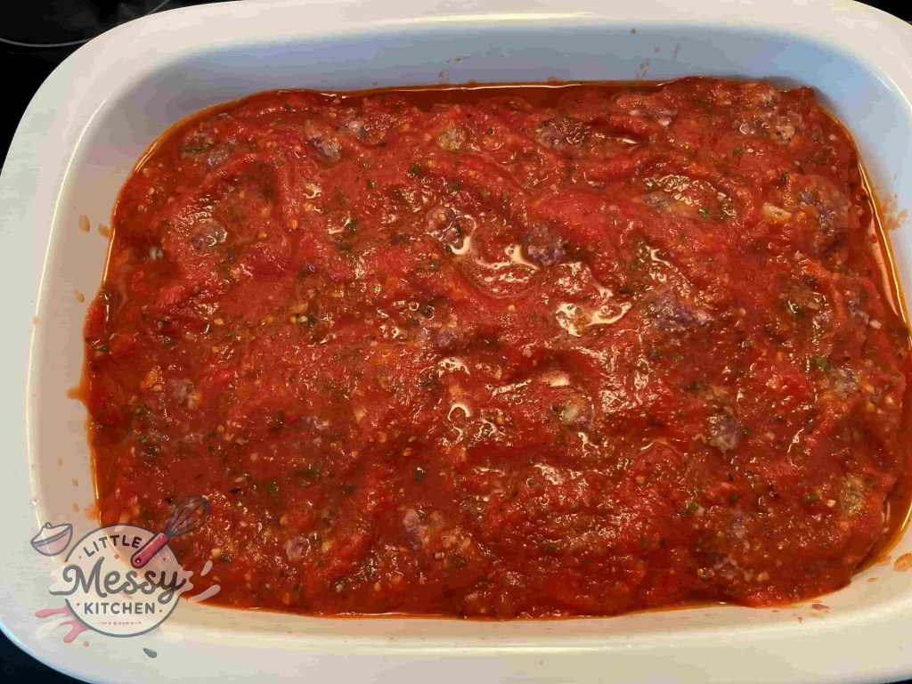 Baking dish with meatballs covered in marinara sauce, ready for baking.
