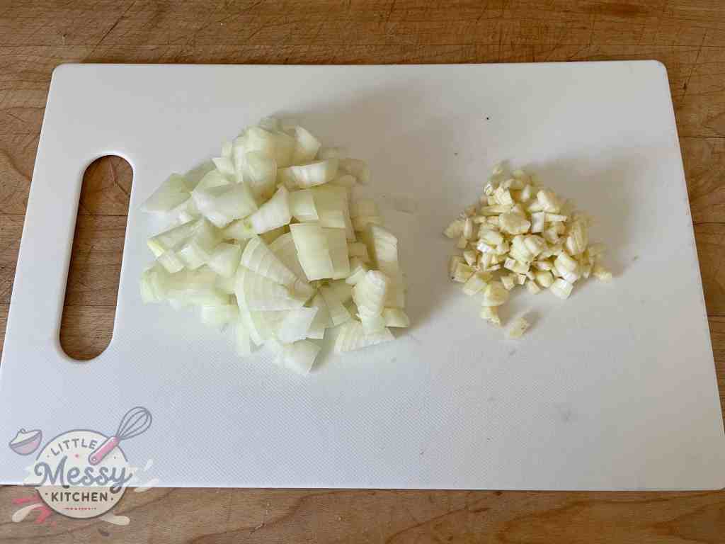 Diced onion and garlic on a cutting board.