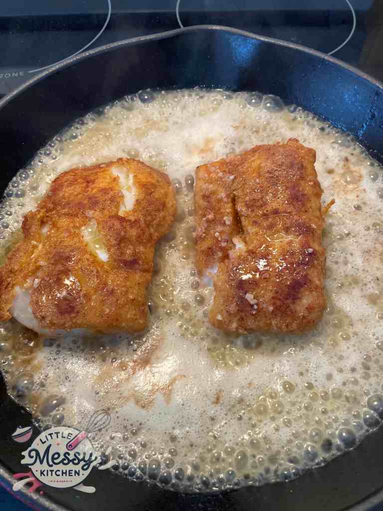 Butter mixture poured over cod filet in cast iron skillet.