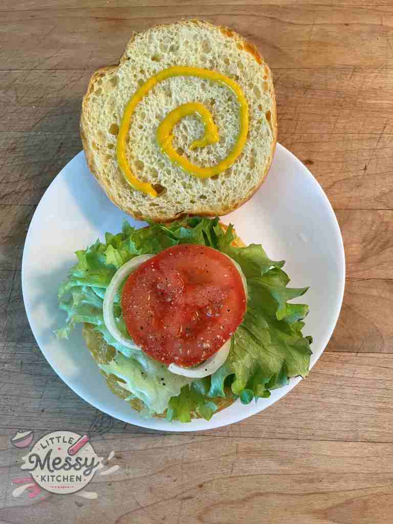 Lettuce, tomato slice and onion slices, layered on an opened burger bun