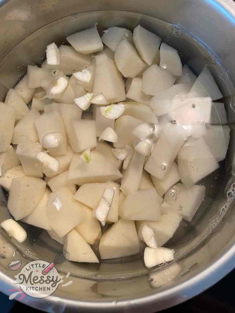 Diced potatoes and garlic in a saucepan filled with water.