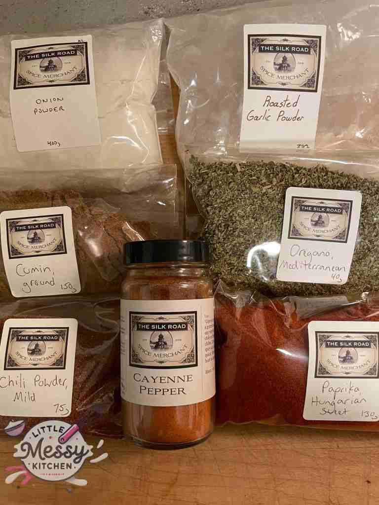 Presented spices: cayenne pepper, chili powder, ground cumin, onion powder, oregano, and roasted garlic.
