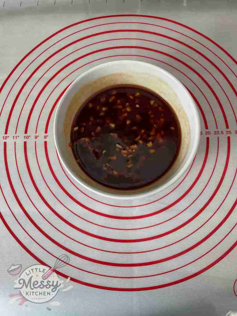 Sauce ingredients combined in a bowl: soy sauce, honey, ketchup, minced garlic, apple cider vinegar, grated ginger, and red pepper flakes.