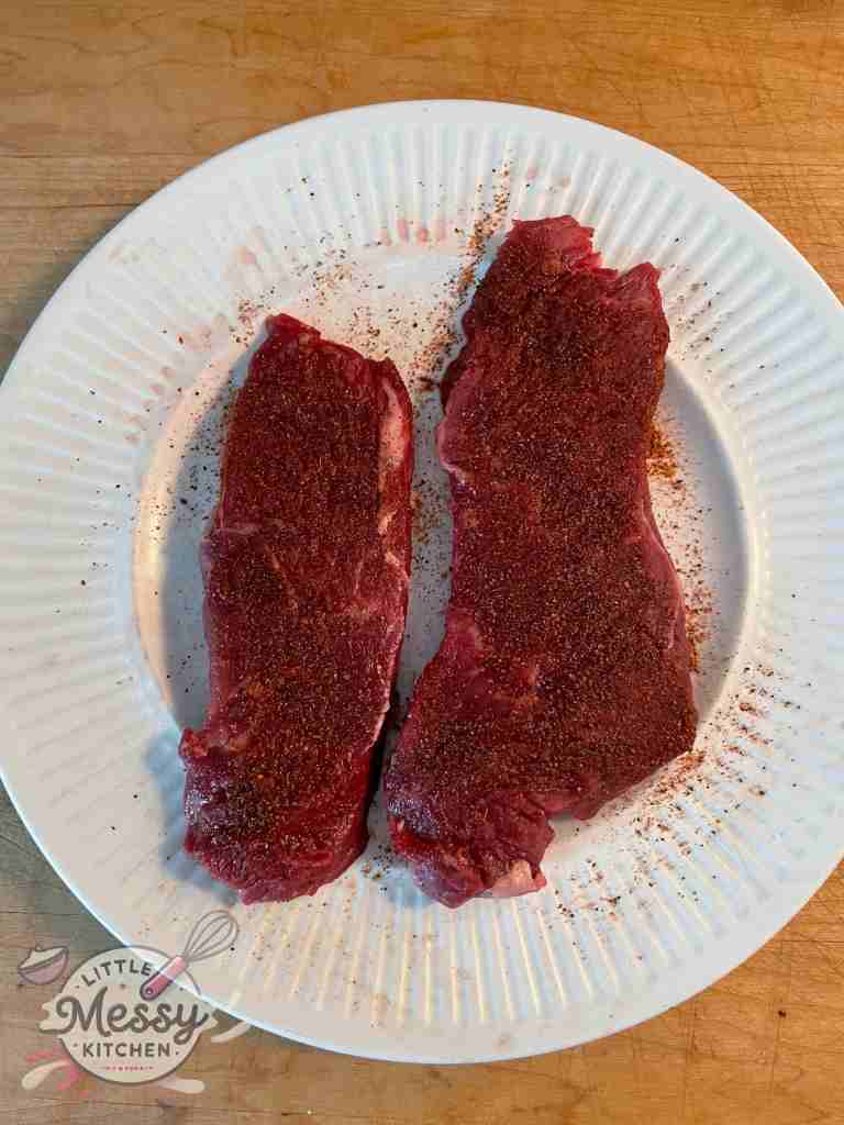 Seasoned steaks on a plate.