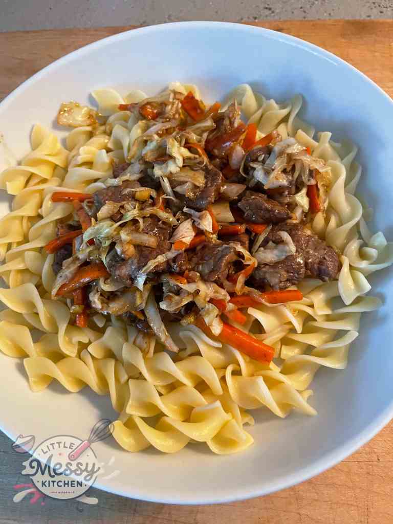 Beef & cabbage stir fry served on a bed on noodles
