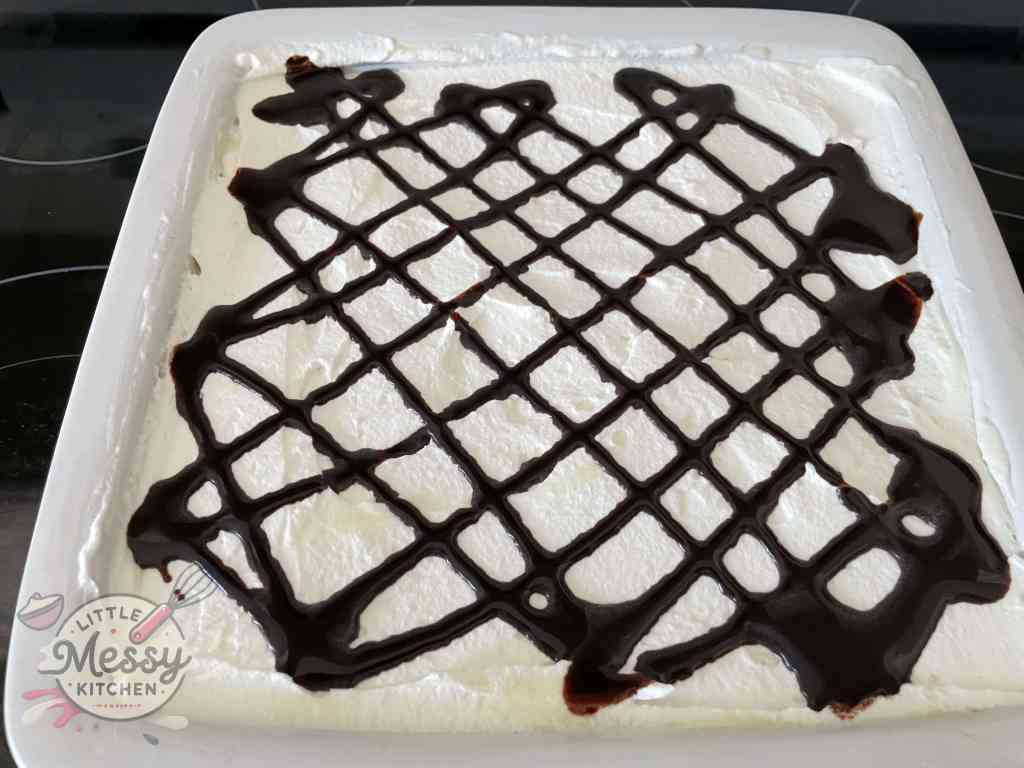 Whipped cream and chocolate syrup added on top of cream filling.