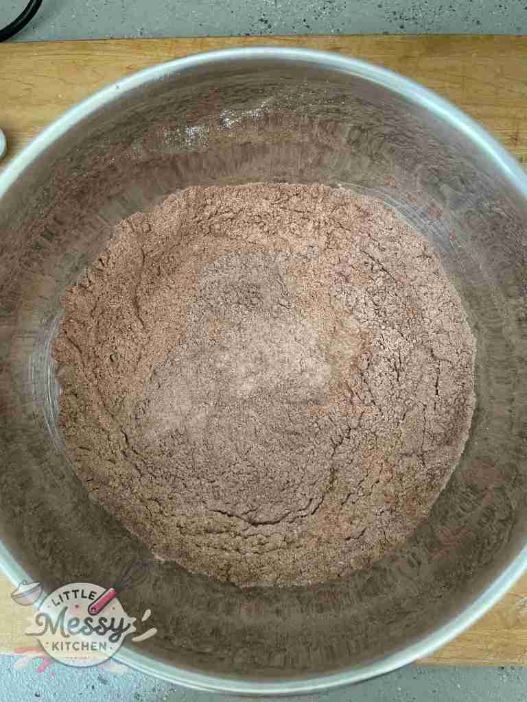 Flour, cocoa powder, baking powder, baking soda, and salt mixed together in a large bowl.