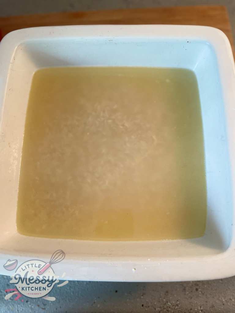 Boiled water poured on top of Uncooked rice in a baking dish.
