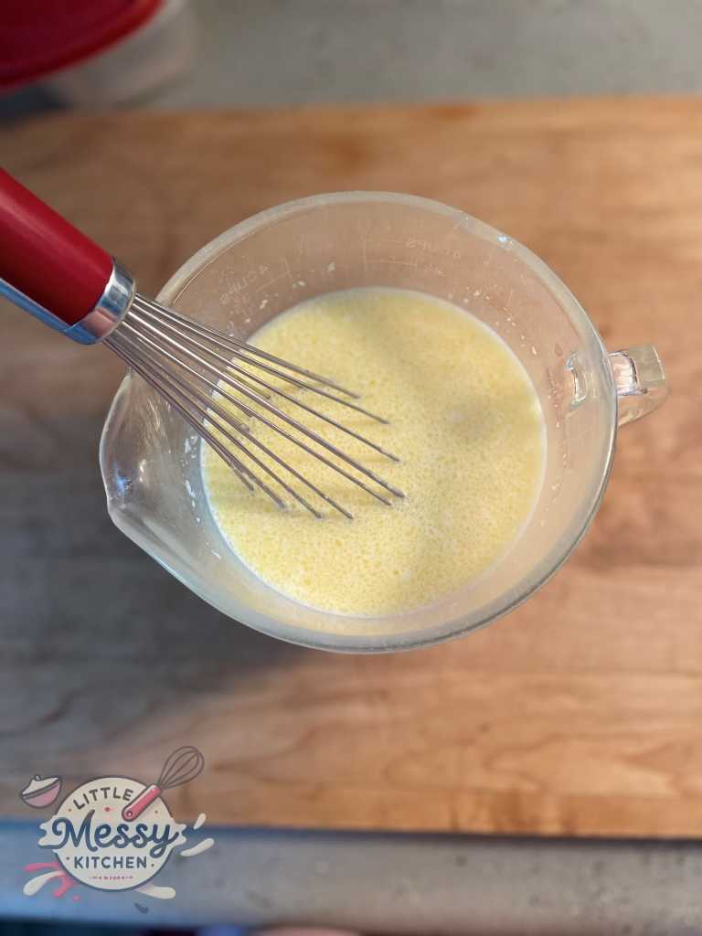 Milk, eggs, vanilla essence, almond essence and melted butter mixed in a bowl.