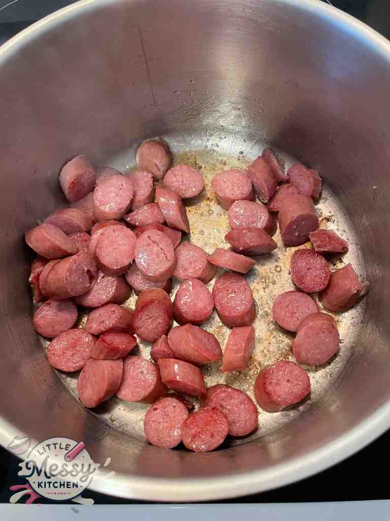 Sausages slices cooking in a stockpot.