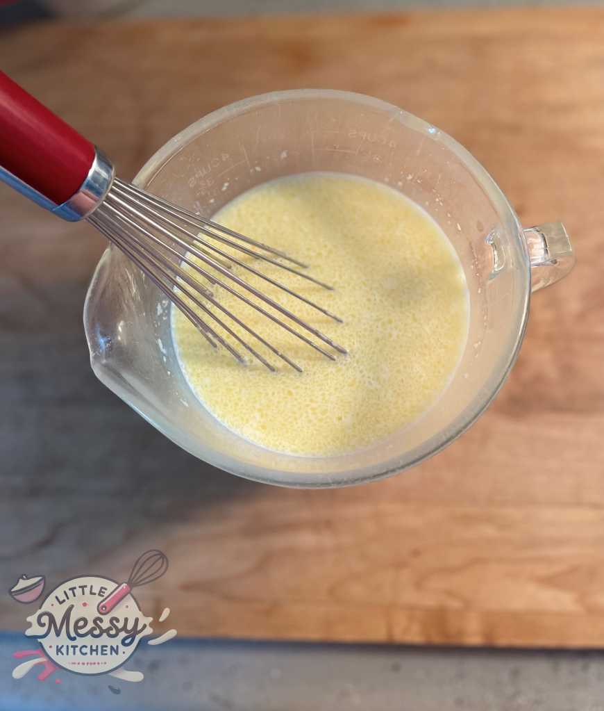 Milk, eggs, vanilla essence, and melted butter mixed in a bowl.