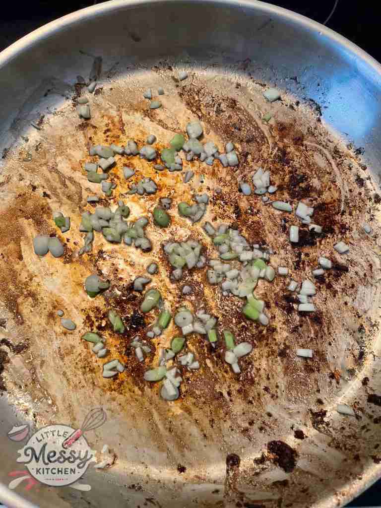 Garlic and green onions sauteing in frying pan.