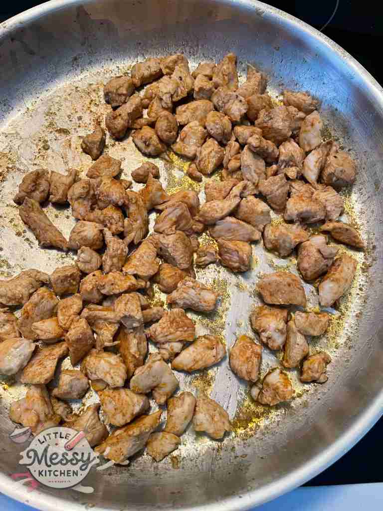 Marinated chicken cooking in frying pan.