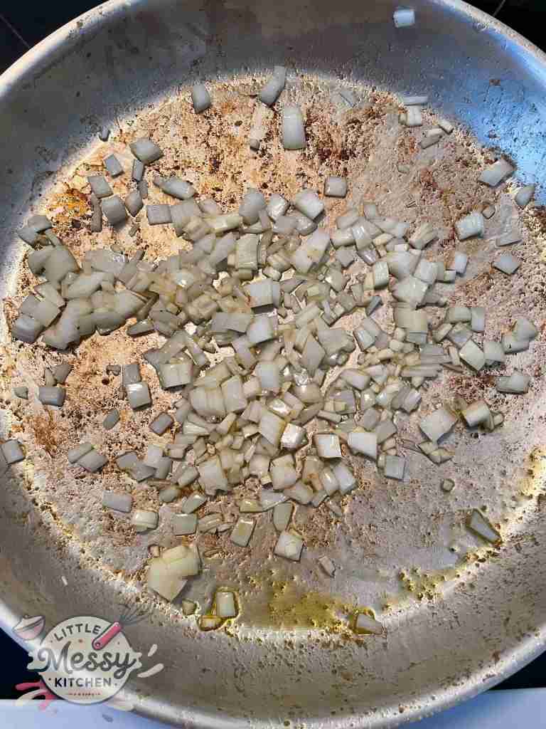 Diced onions and garlic sauté in a frying pan.