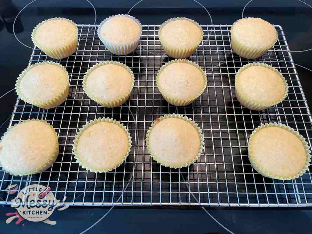 12 baked cupcakes cooling on a rack.