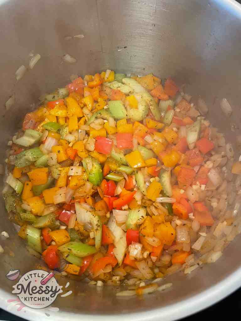 Onions, celery, bell peppers diced cooking in a stockpot