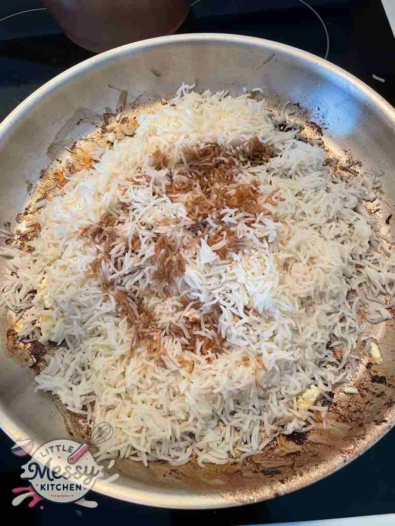 Rice and soy sauce added to frying pan.