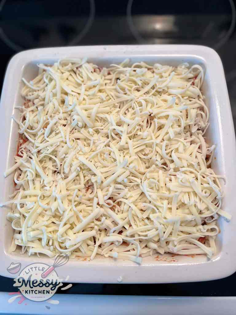 Grated cheese added to the pasta in a baking dish.