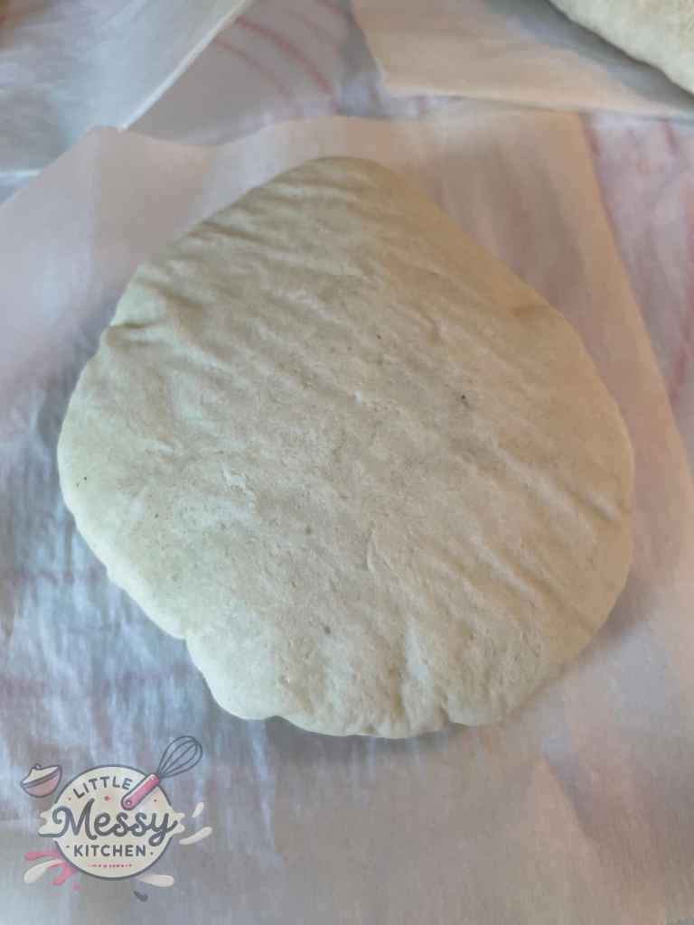 Freshly baked homemade pita bread cooling on parchment paper, soft and ready to enjoy.