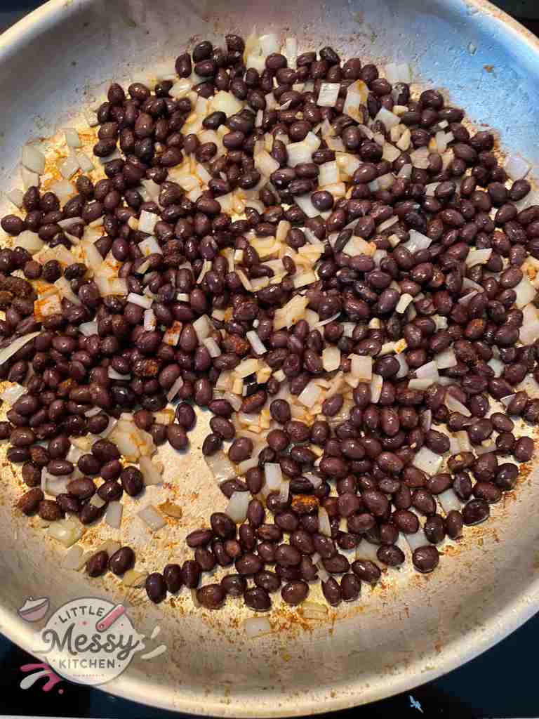 Black beans added to the diced onions and garlic in frying pan.