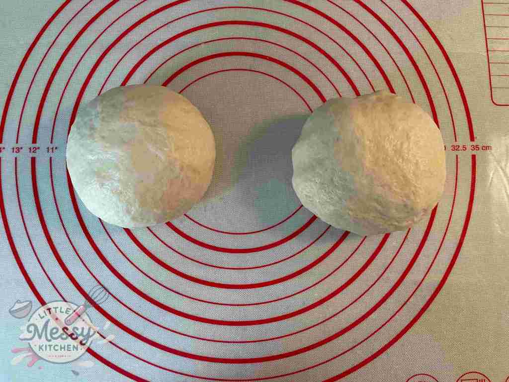 Two equally divided ball of dough on a pastry mat.