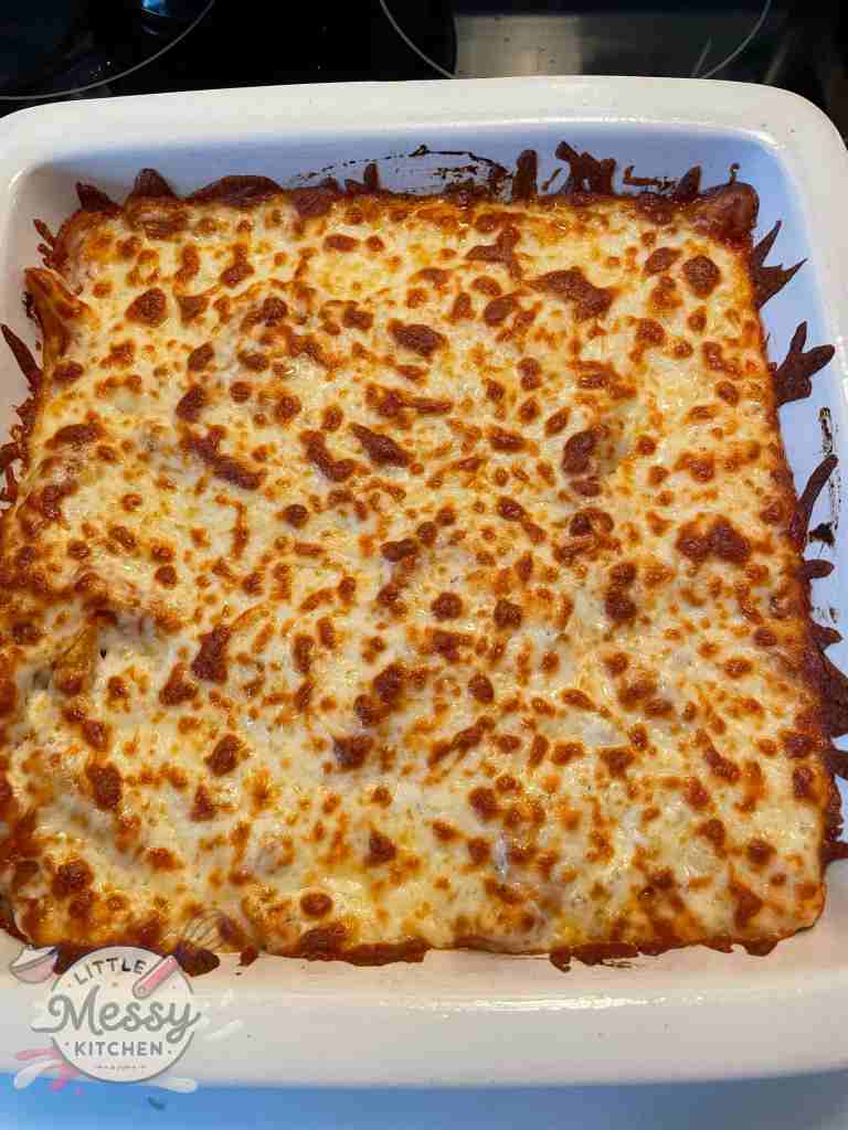 Golden-brown baked pasta topped with melted cheese in a white baking dish.