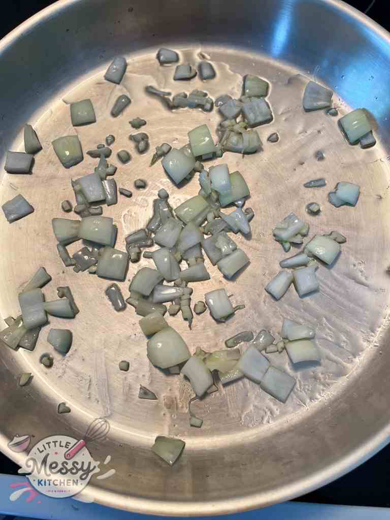 diced onions and minced garlic cooking in frying pan.