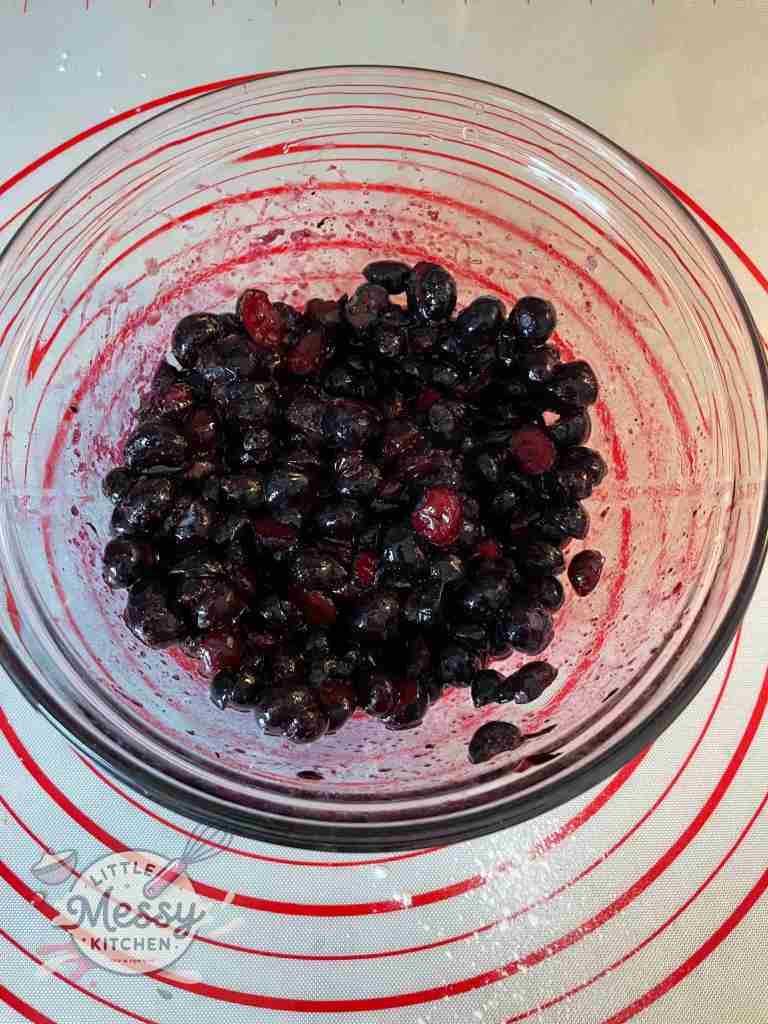 Sliced blueberries and sugar combined in a mixing bowl.