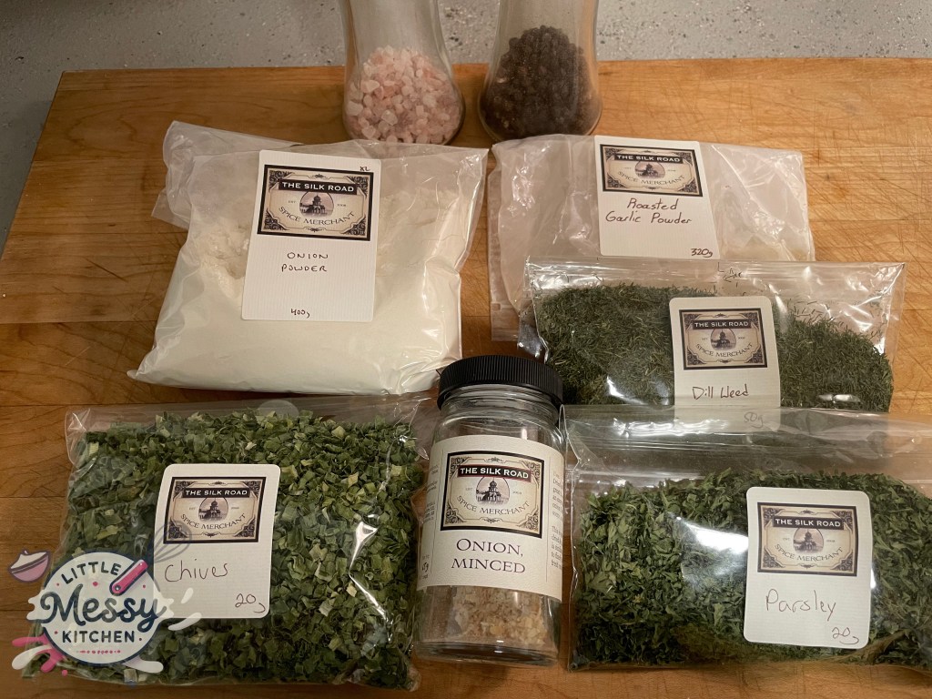 Assorted spices and herbs: parsley, dill, garlic powder, onion powder, onion flakes, pepper, chives, and salt displayed on a surface.