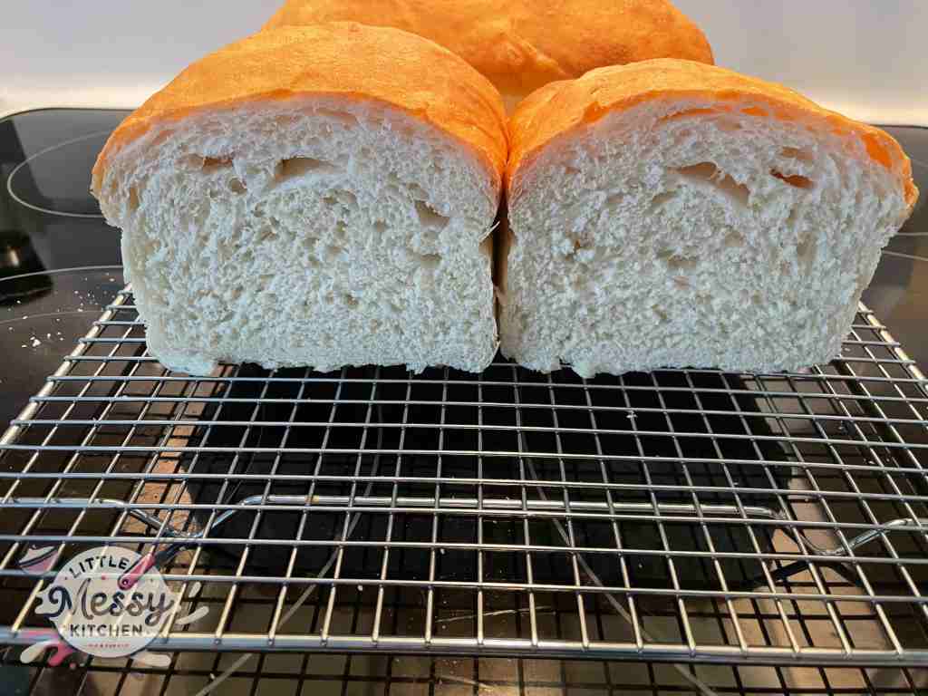 Cooked bread cut in 2 on a cooling rack.