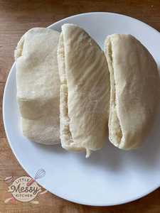 Three freshly baked homemade pita breads served on a white plate, soft and ready to fill with your favorite ingredients.