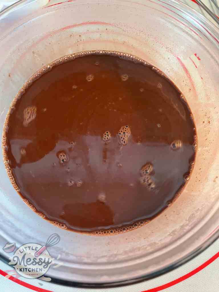 Chocolate chips, cocoa powder and boiling water combined in a mixing bowl.