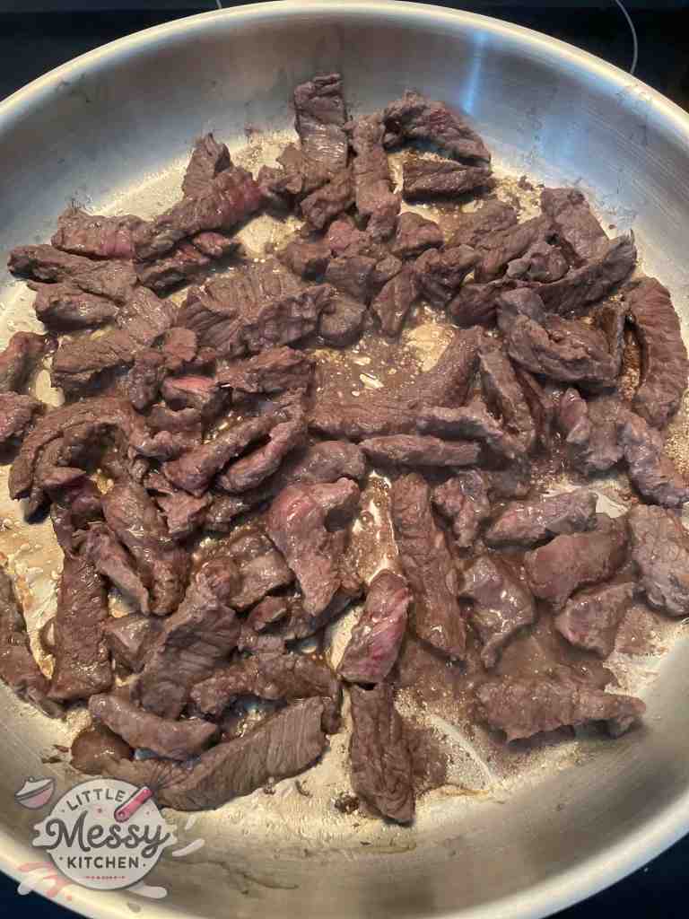 Top sirloin steaks strips cooking in skillet.