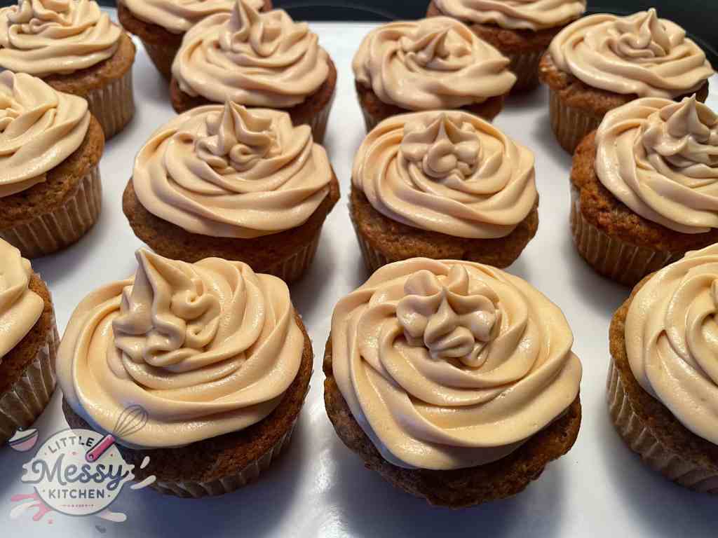 Carrot cake cupcakes with frosting spread on top.