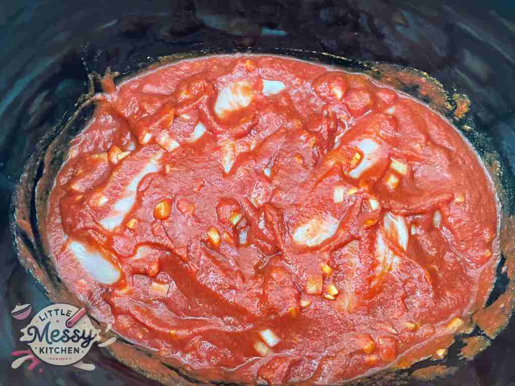 Sauce mixture and chicken breast set in slow cooker.