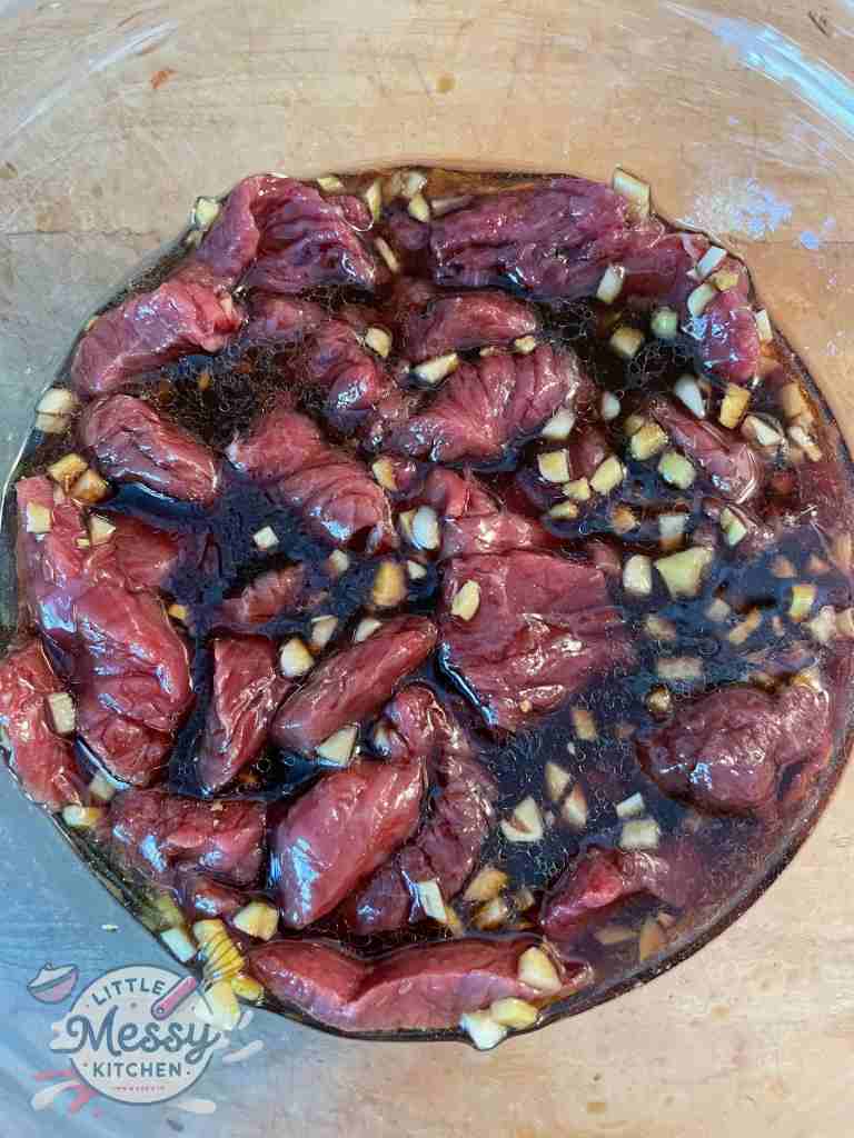 Steak strips marinating in mixing bowl.