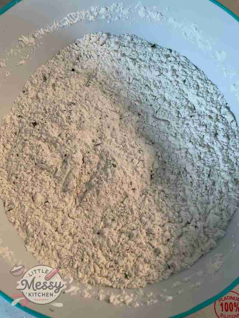 Flour and herbs (parsley, oregano, basil and garlic) mixed in a bowl.