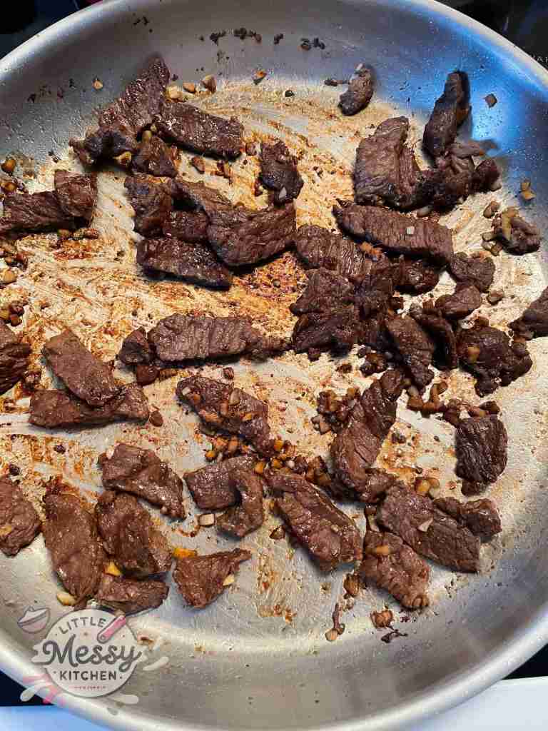 Marinated Steak cooking in frying pan.
