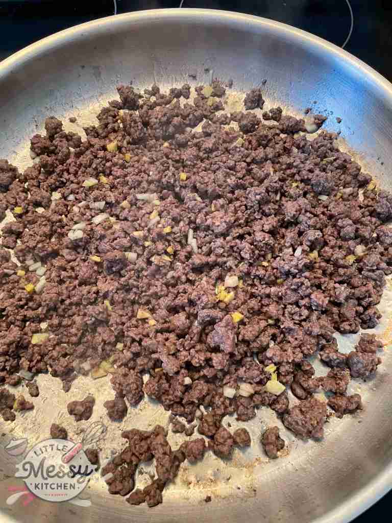 Ground beef, garlic and ginger cooking in frying pan.