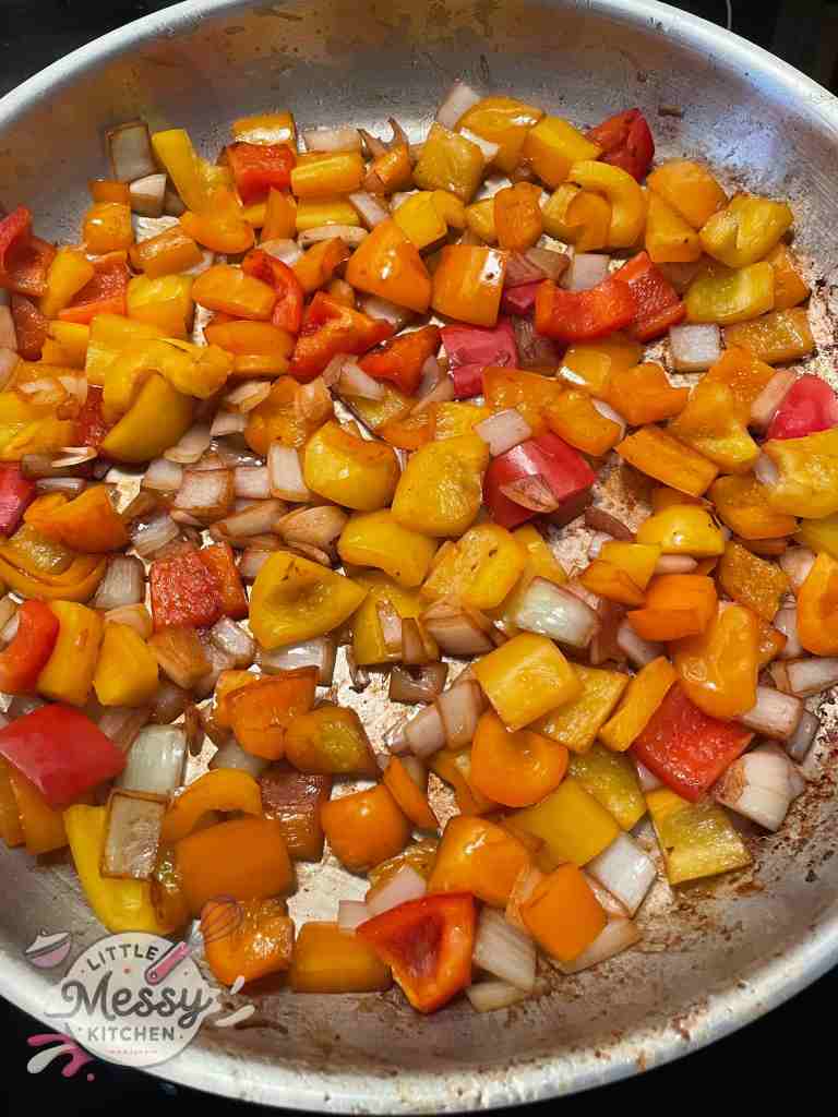 Pepper and onions sauté in a frying pan.