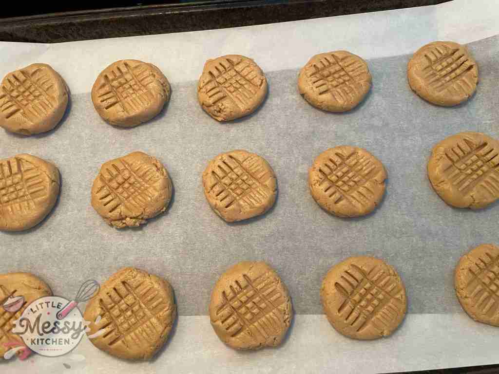 Uncooked cookie dough on a baking sheet divided in 12 cookies.