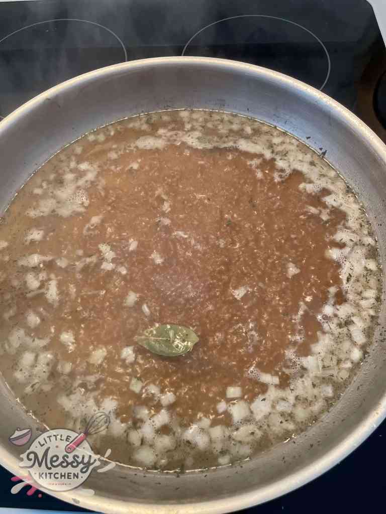 Beef broth and seasoning boiling in skillet.