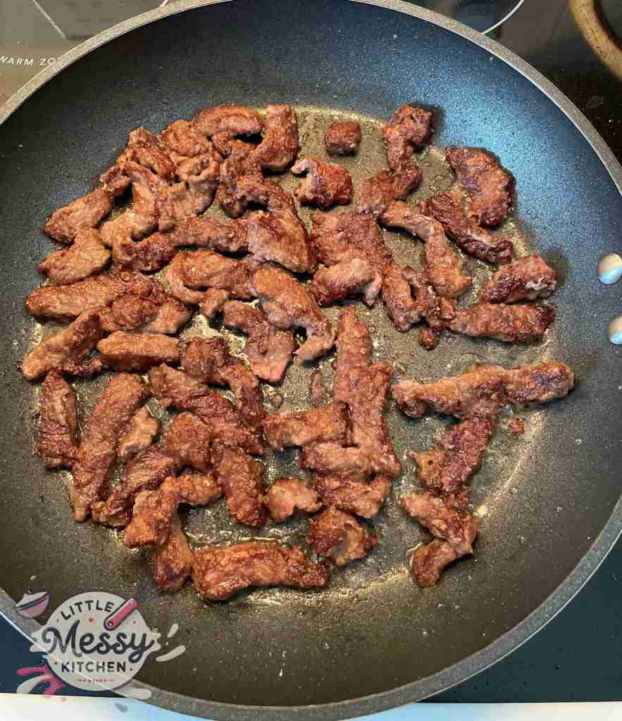 Steak slices cooking in frying pan.