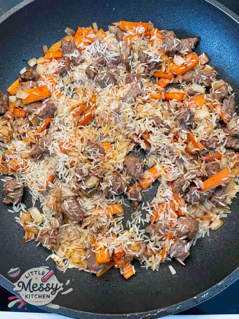 Beef, rice and spices added to the skillet.