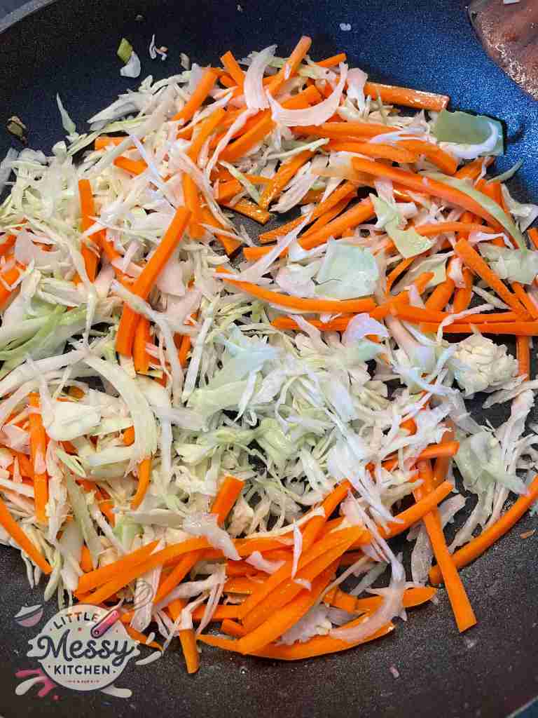 Cabbage and carrots, sauteing in a skillet.