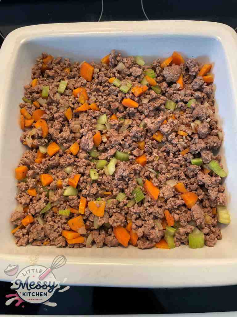 Ground beef and vegetables added to an 8x8 baking dish.