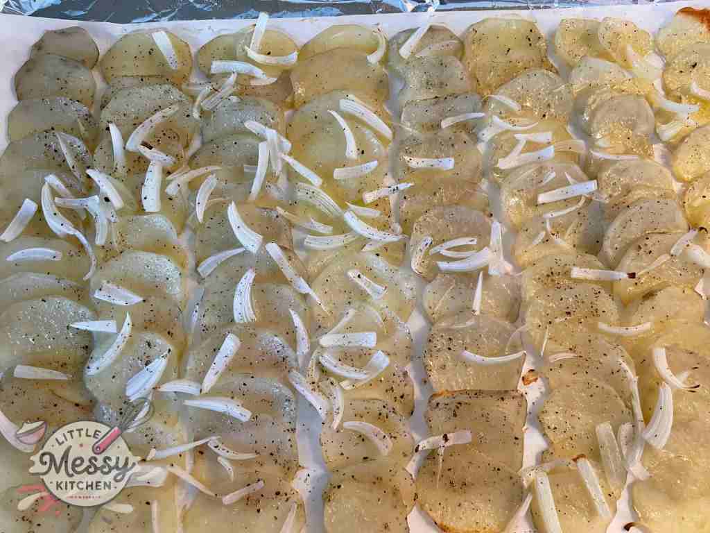 Potato slices and onion on a baking sheet fresh out of the oven. 
