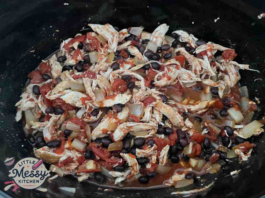 Tomato mixture, shredded chicken and black beans in slow cooker.