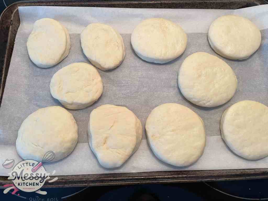 Disk shaped english muffin dough on a baking sheet